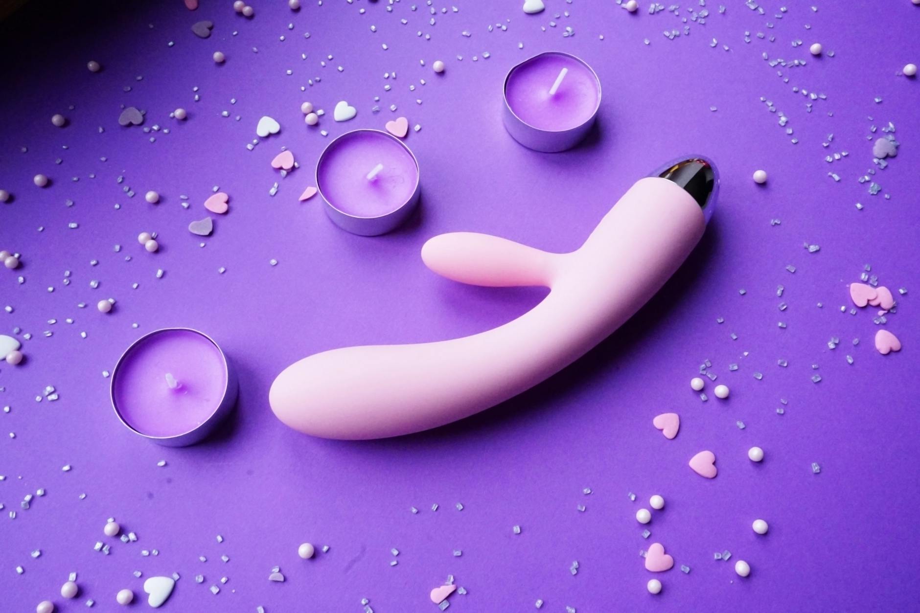 Růžový Lemon vibrator na fialovém pozadí se svíčkami a romantickou dekorací
