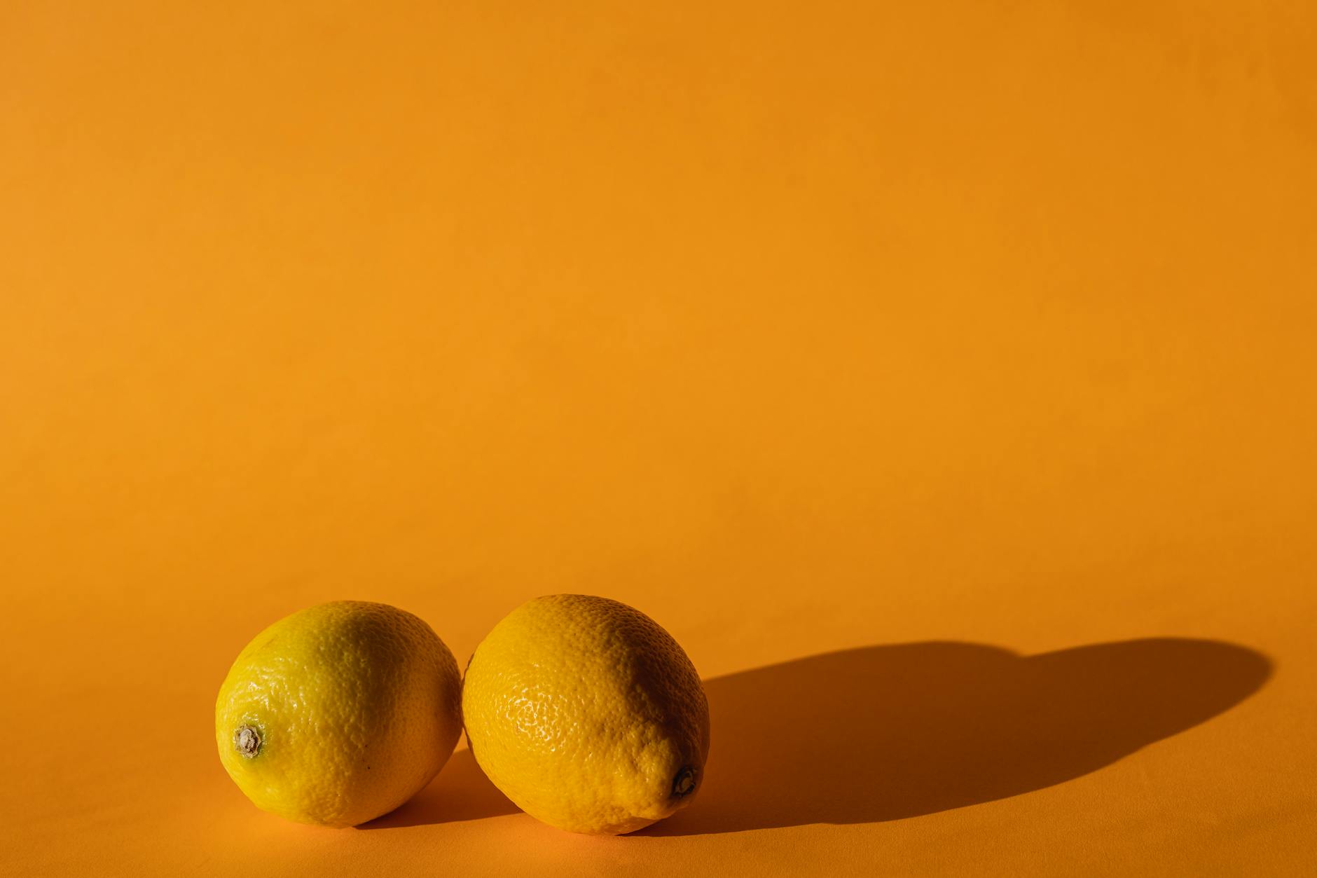 Ruka drží citron na žluté pozadí symbolizující obnovu a svěžest